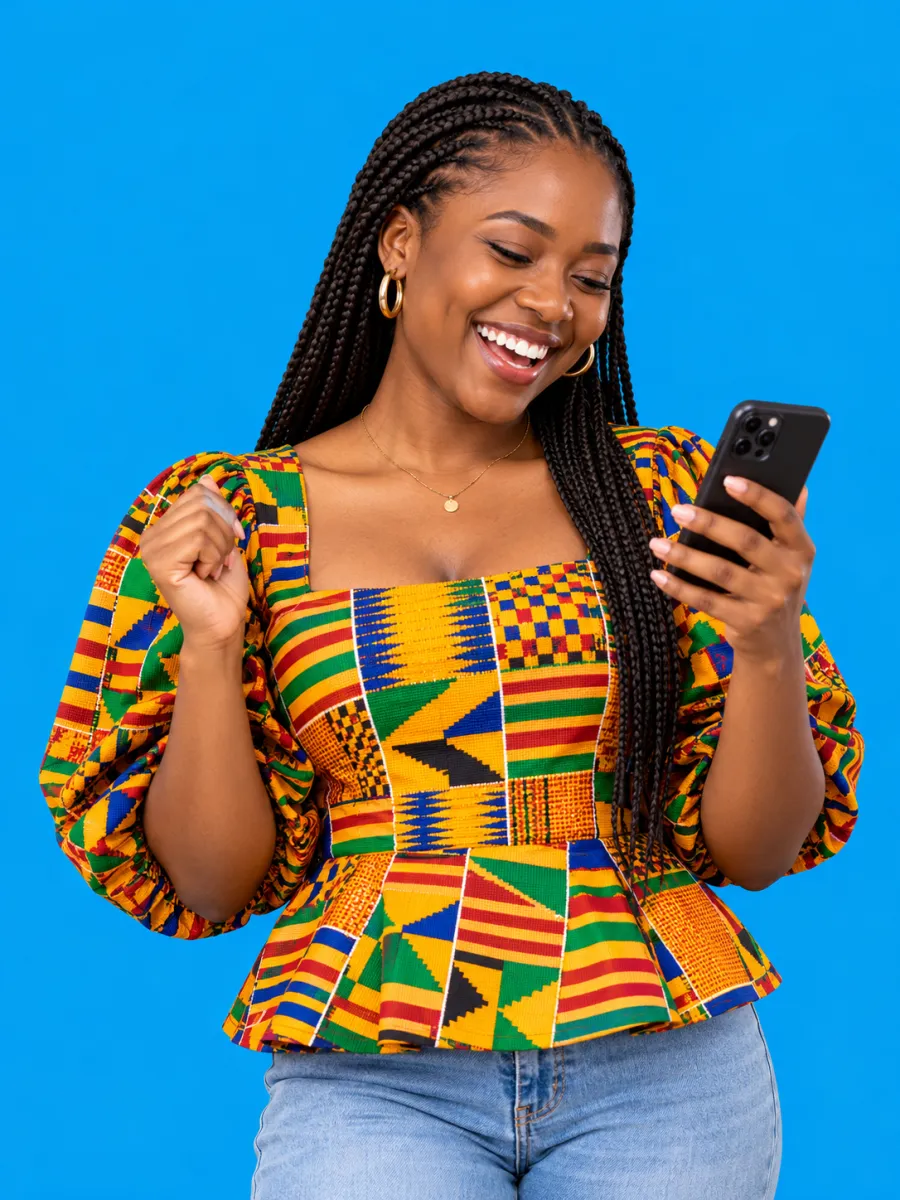 Joyful traveller in kente top using her phone